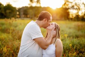 A romantic sunset silhouette of a couple sharing an intimate moment in a field.