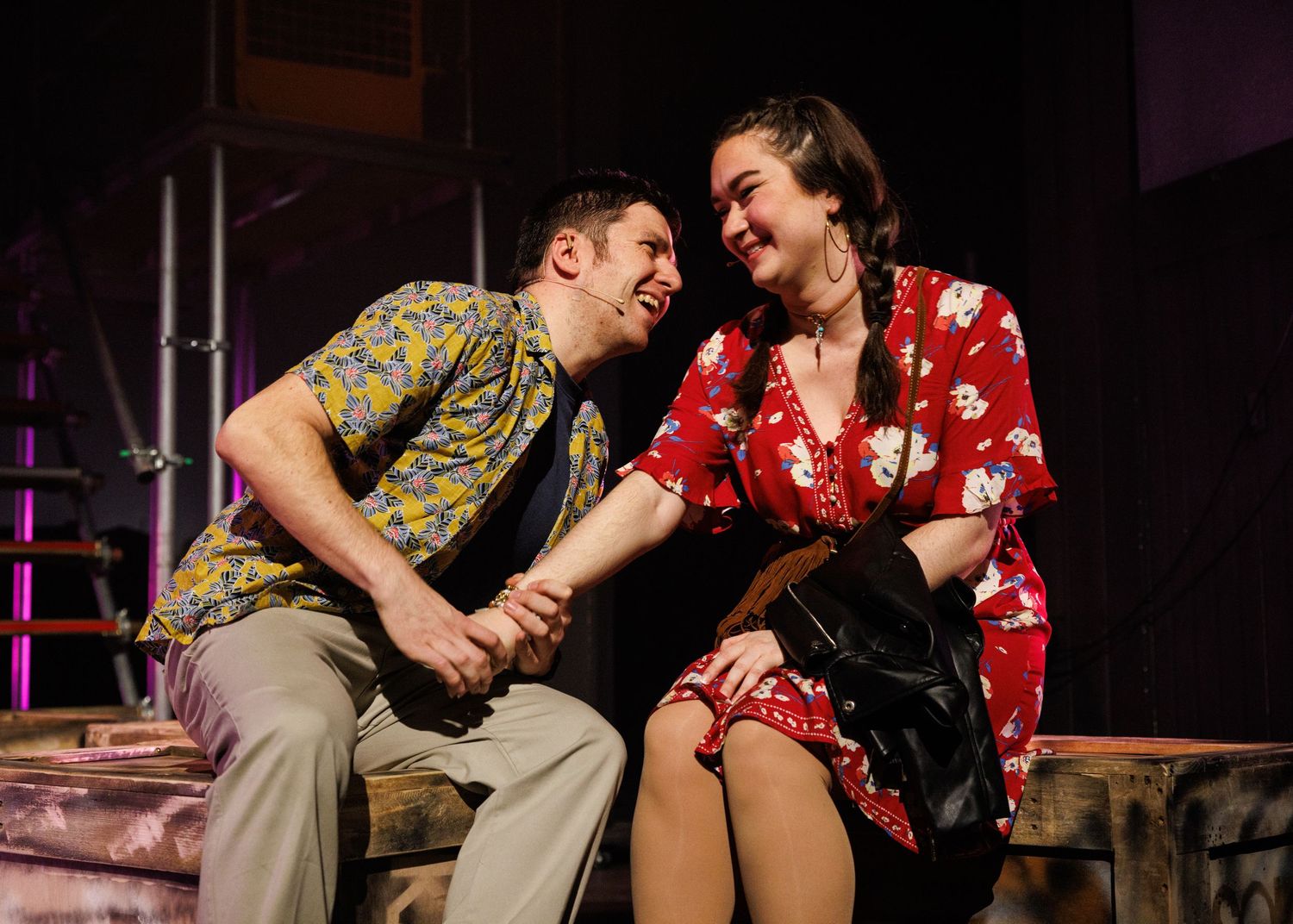 Two performers in vintage clothing share intimate moments during a theatrical stage performance.