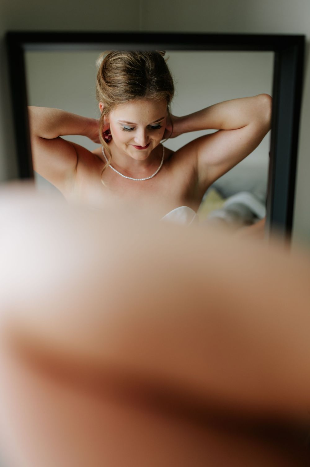 Close-up portrait of someone wearing a white top against a soft blurred background.