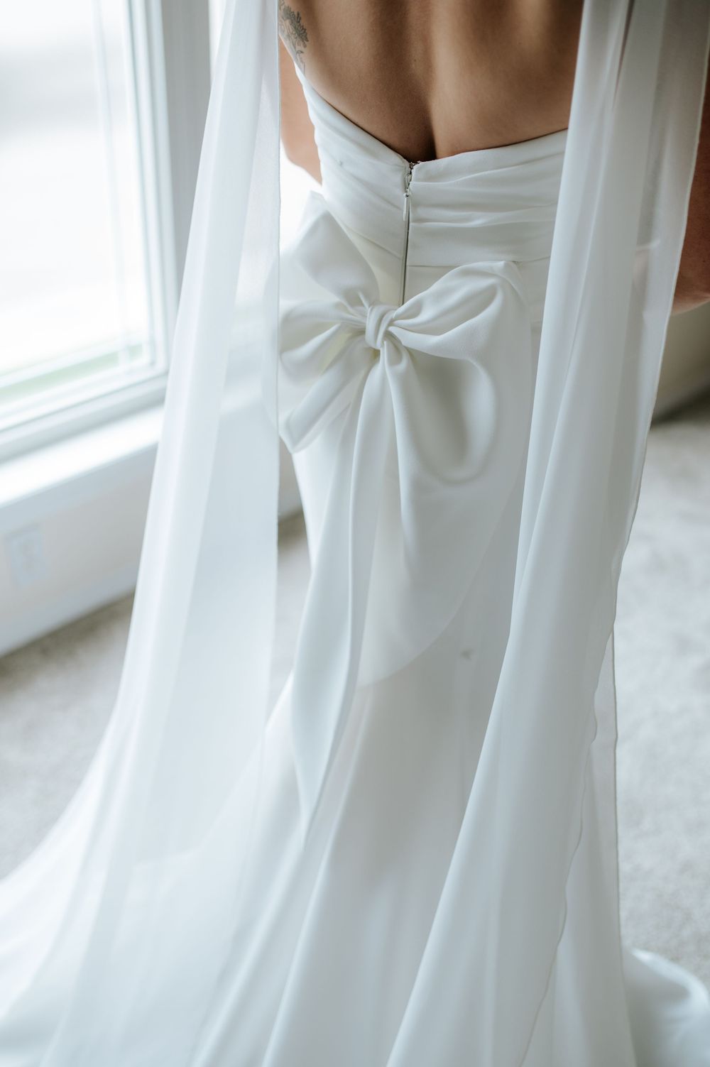 Close-up detail of an elegant white wedding dress bow on the back.