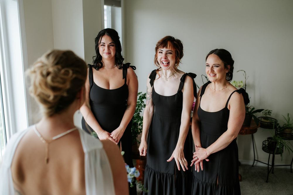 Bridesmaids in matching black dresses share joyful moments during a wedding celebration.