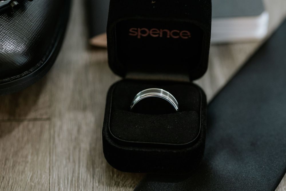 A black ring box sits on a wooden surface in dramatic lighting.