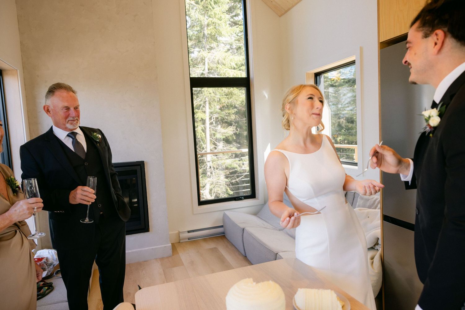 A wedding celebration with guests and the newlyweds in formal attire gathered in a bright indoor venue.