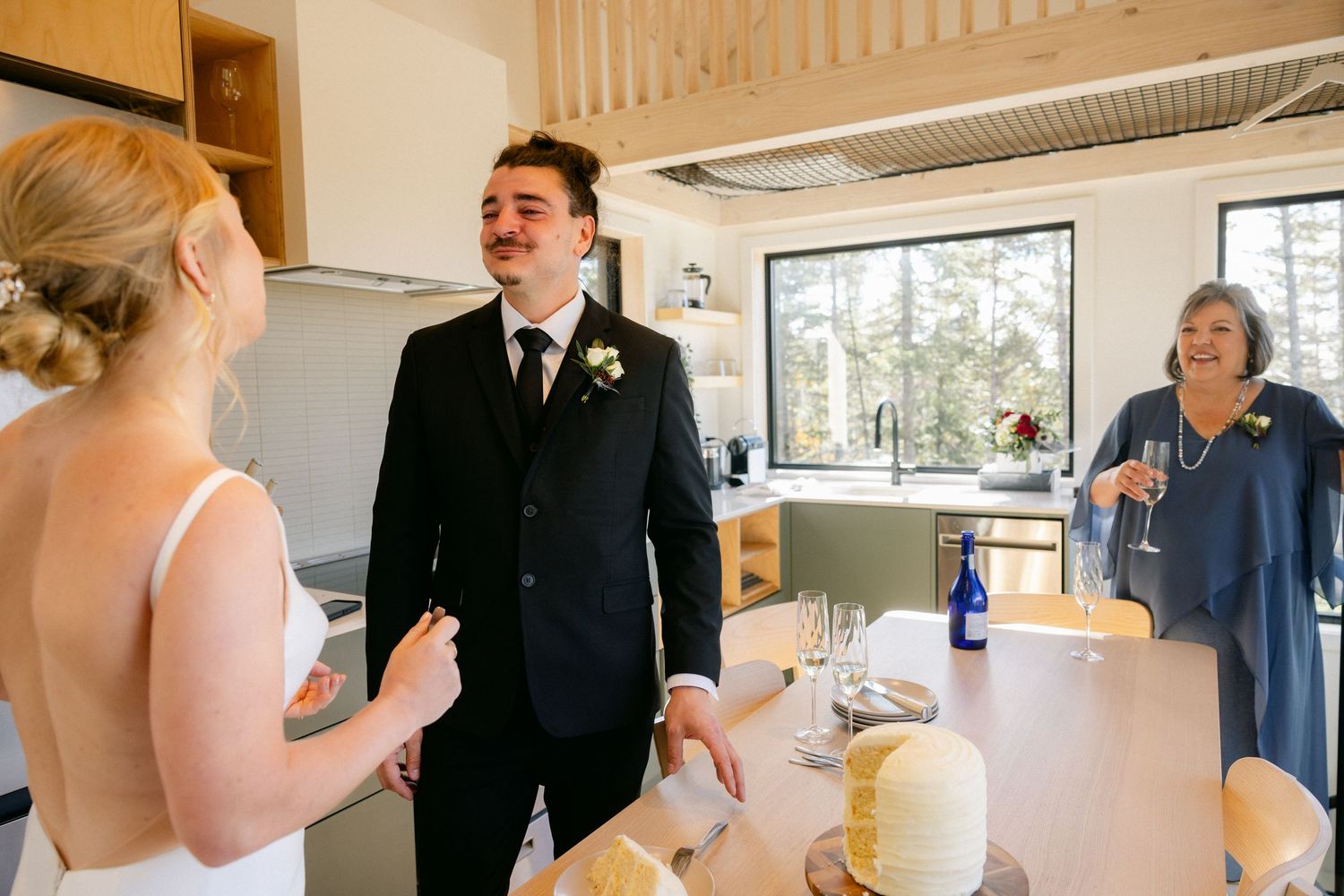 A joyful moment shared between people in a bright kitchen during what appears to be a wedding celebration.
