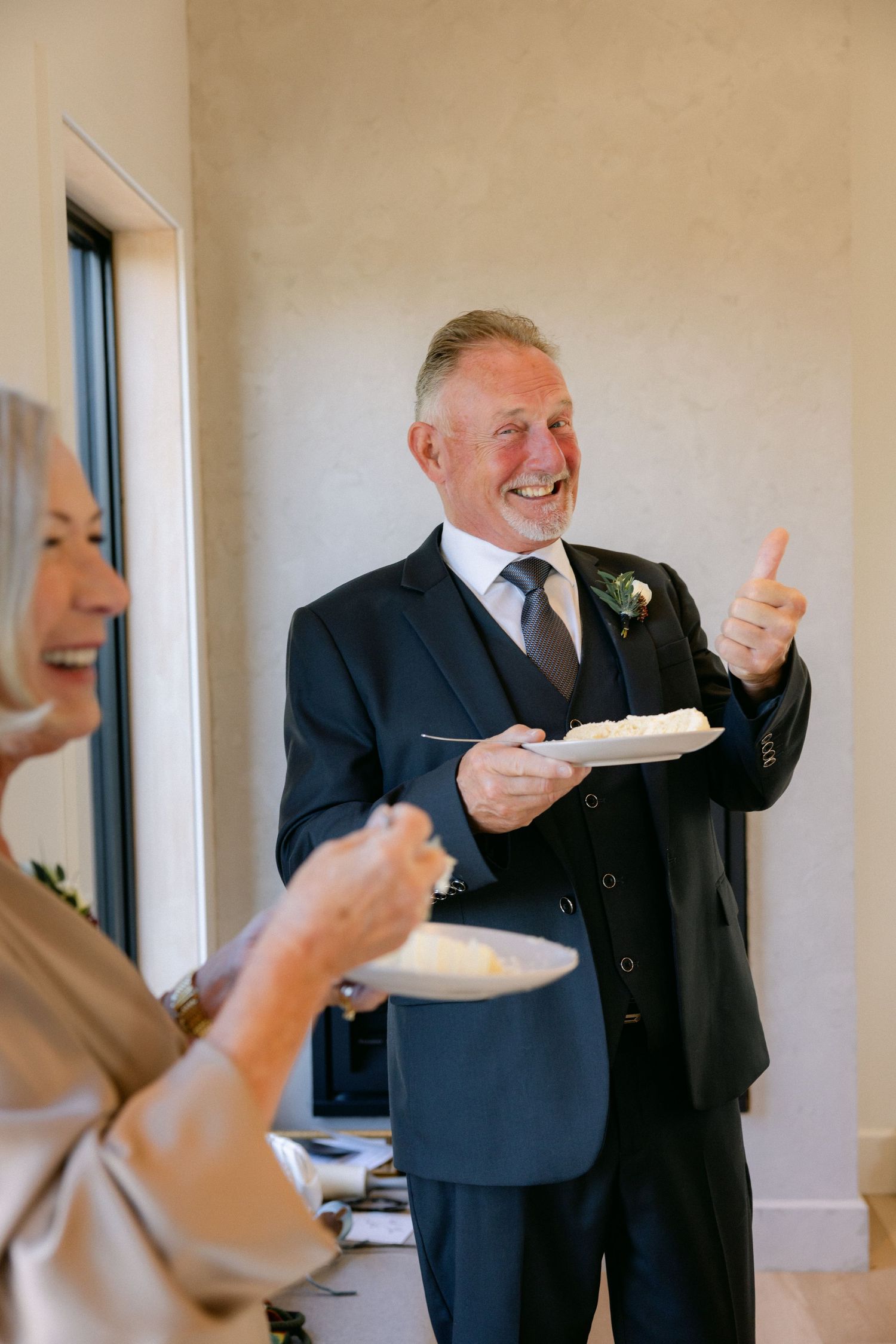 Two people in formal attire share a joyful moment while eating cake at a special event.