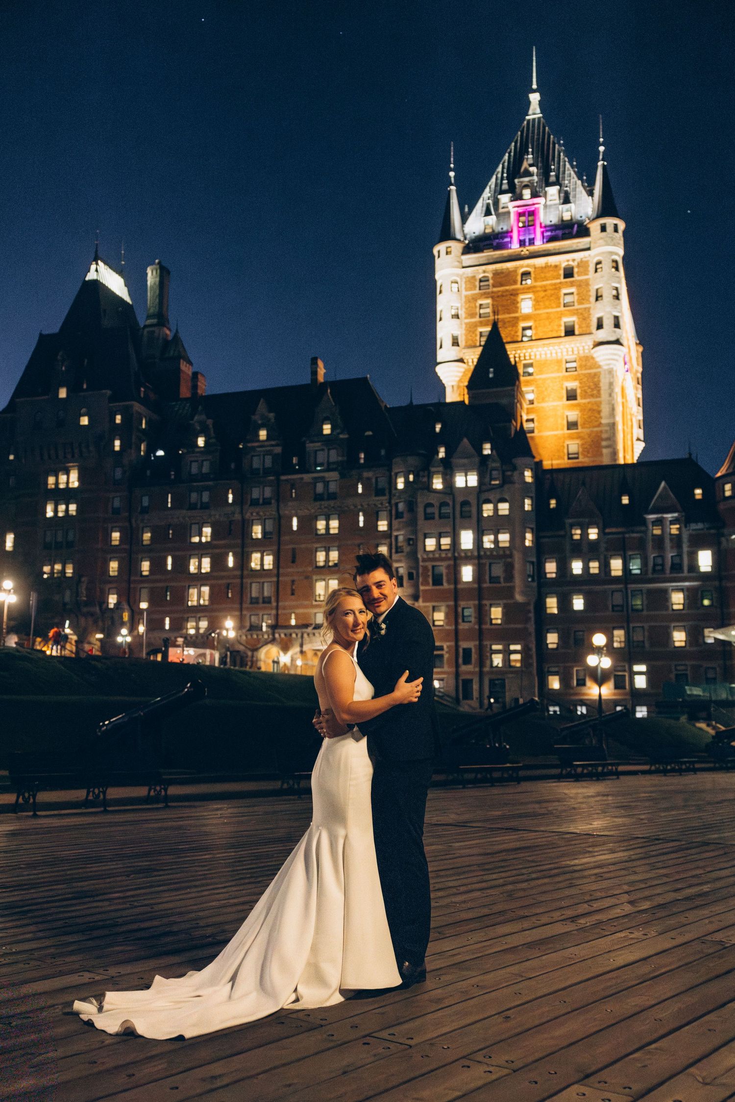 Wedding couple dances at night with the illuminated Chateau Frontenac castle in Quebec City as backdrop.