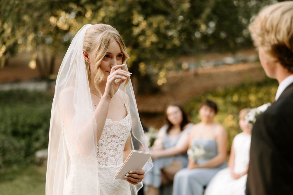 A wedding celebration in a garden setting with guests mingling during golden hour lighting.