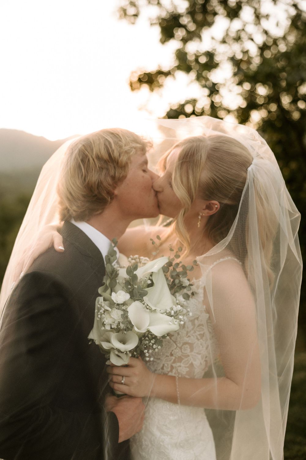 Romantic sunset wedding kiss captured in a series of intimate moments with flowing veil.