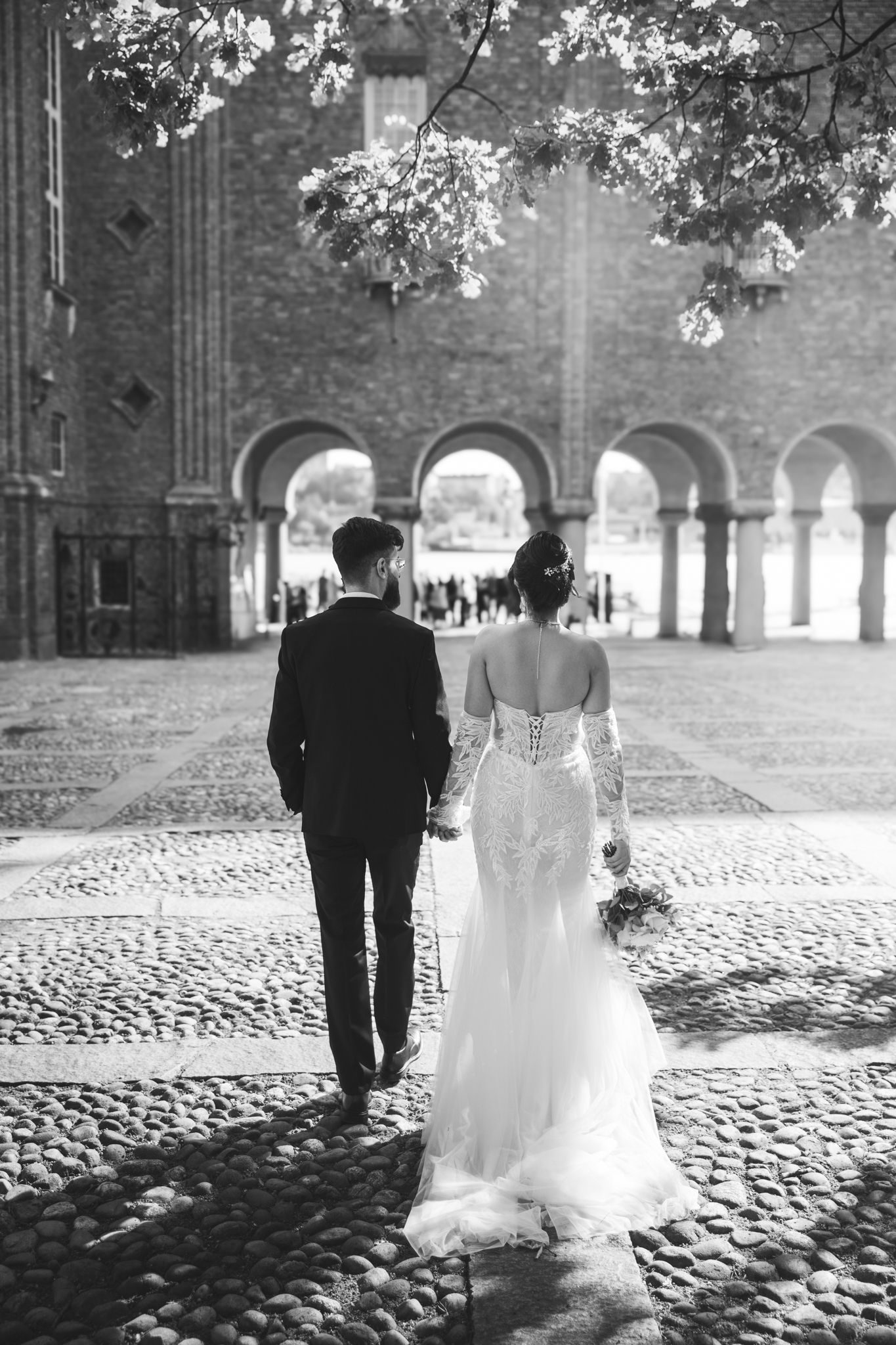 A black and white photo sequence shows a couple walking along a cobblestone path near a historic church building.