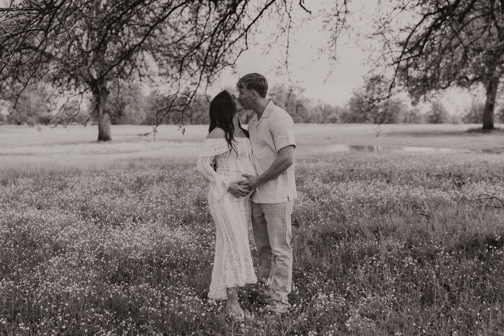 Black and white photo series showing a romantic couple embracing in a wildflower meadow at sunset.