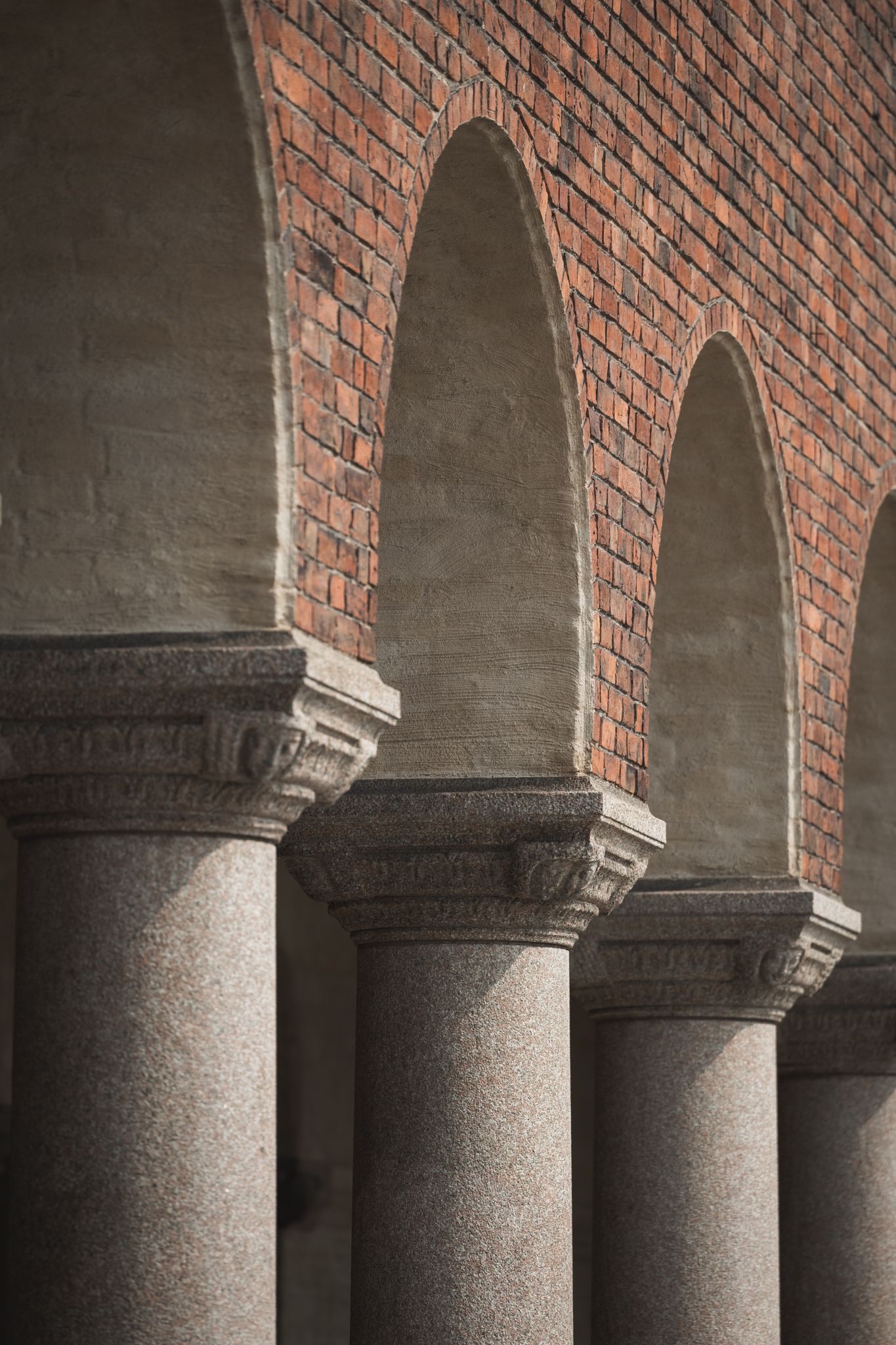 Row of brick arches with granite columns in classical architecture style creates repetitive geometric pattern. Stadshuset arkitektur.