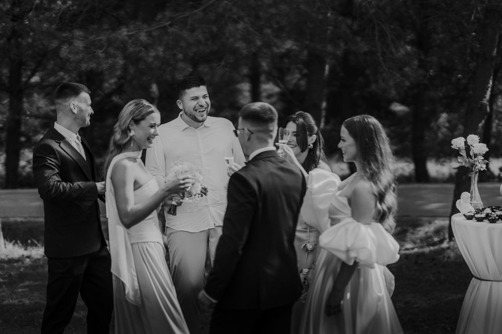 Black and white photo of wedding guests mingling at outdoor reception.