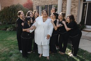 Wedding party members in black and white attire pose together for group photos outside a brick building.