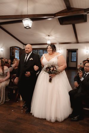 A wedding ceremony in a rustic venue with exposed wooden beams and warm lighting.