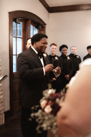 A joyous wedding celebration shows people dancing and laughing in a rustic indoor venue with brick walls.