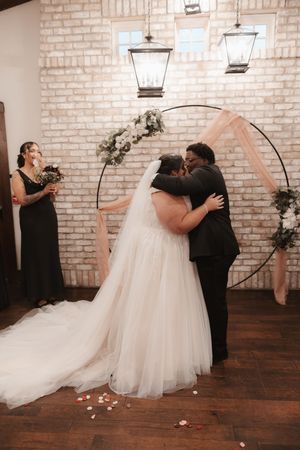 A couple shares a romantic first dance moment in a rustic venue with exposed brick walls and hanging lanterns.