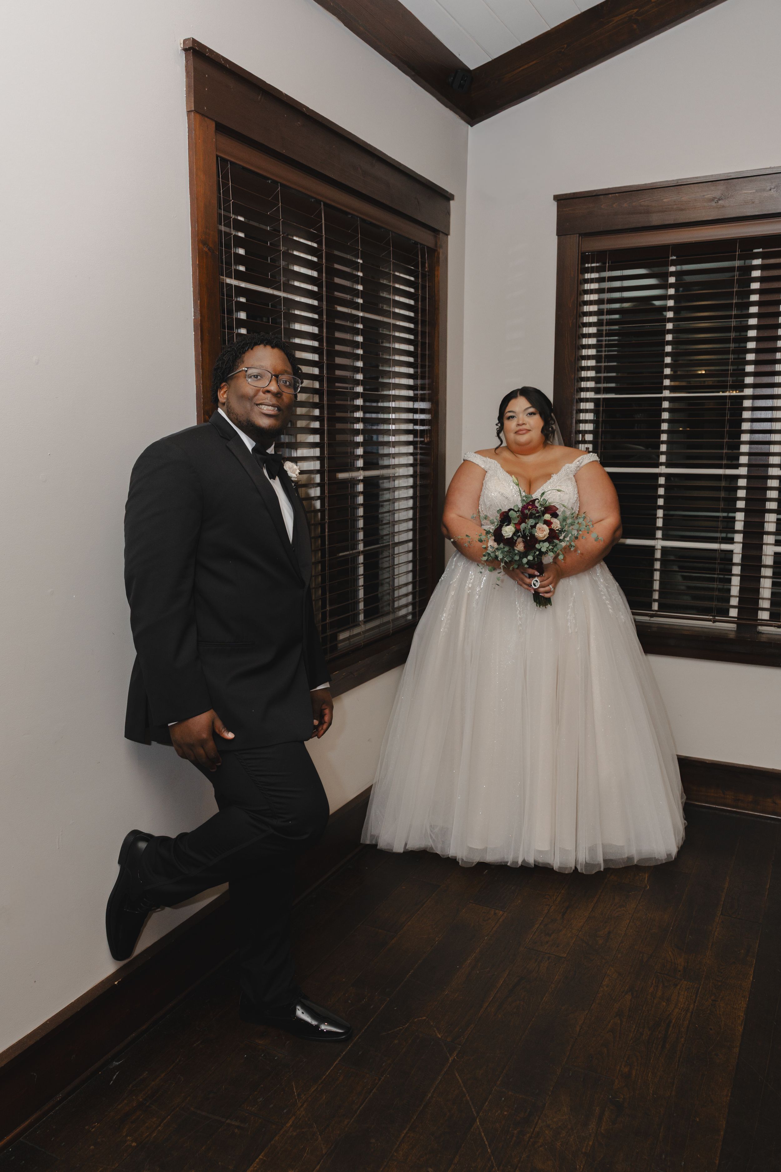 A wedding portrait in an elegant room with dark wooden floors and plantation shutters.
