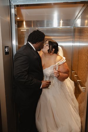 Newlywed couple sharing intimate moments in an elevator on their wedding day.