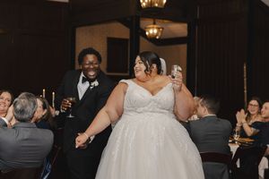 Wedding reception scene in a dimly lit venue with elegant chandeliers and formal attire.