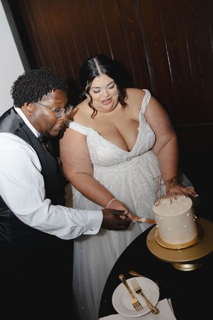A couple shares an intimate moment while cutting their wedding cake together.