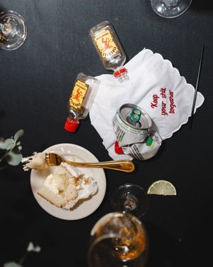Empty cocktail glasses and plates on a dark table with white napkins and scattered drink garnishes.