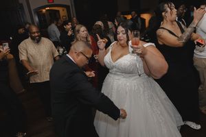 Wedding guests dancing and celebrating together at a dimly lit indoor reception venue.