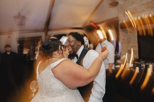 Wedding guests dancing and celebrating on a dimly lit dance floor with warm lighting.