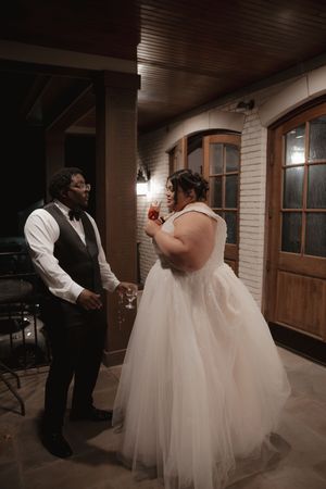 A tender moment between newlyweds in a rustic indoor venue with white brick walls and wooden accents.
