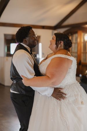 A tender dance moment captured in a rustic venue with natural lighting.