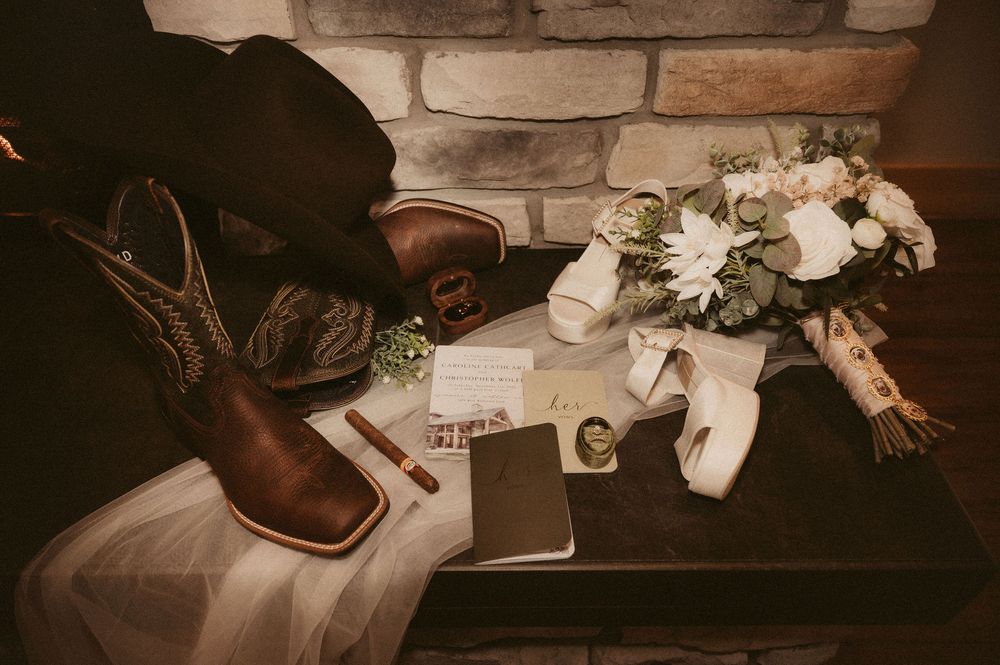 Wedding reception table settings with vintage decor, white flowers, and rustic details in warm lighting.