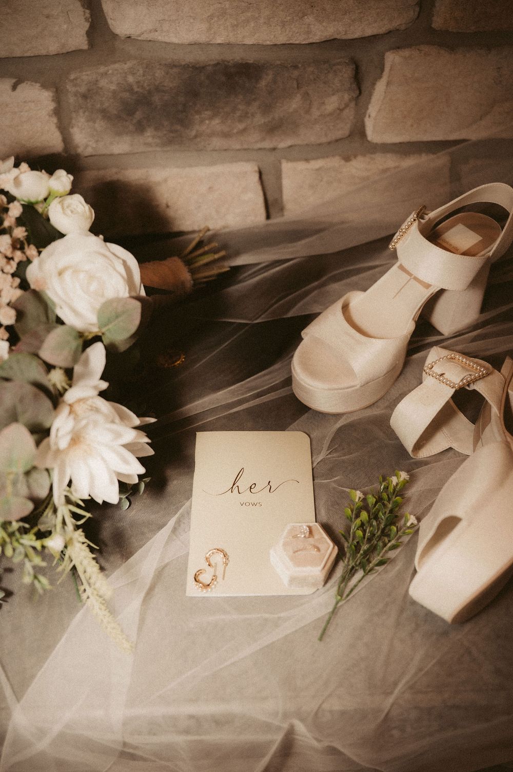Elegant wedding details featuring white roses, delicate tulle fabric, and a handwritten 'her' card in soft sepia tones.
