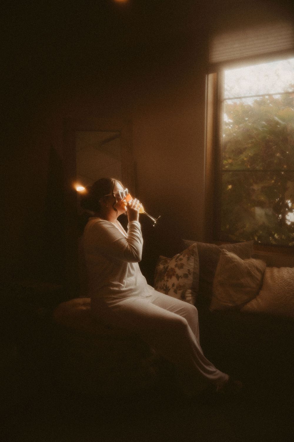 A person sits in moody window light on a couch, creating a series of silhouetted contemplative poses.