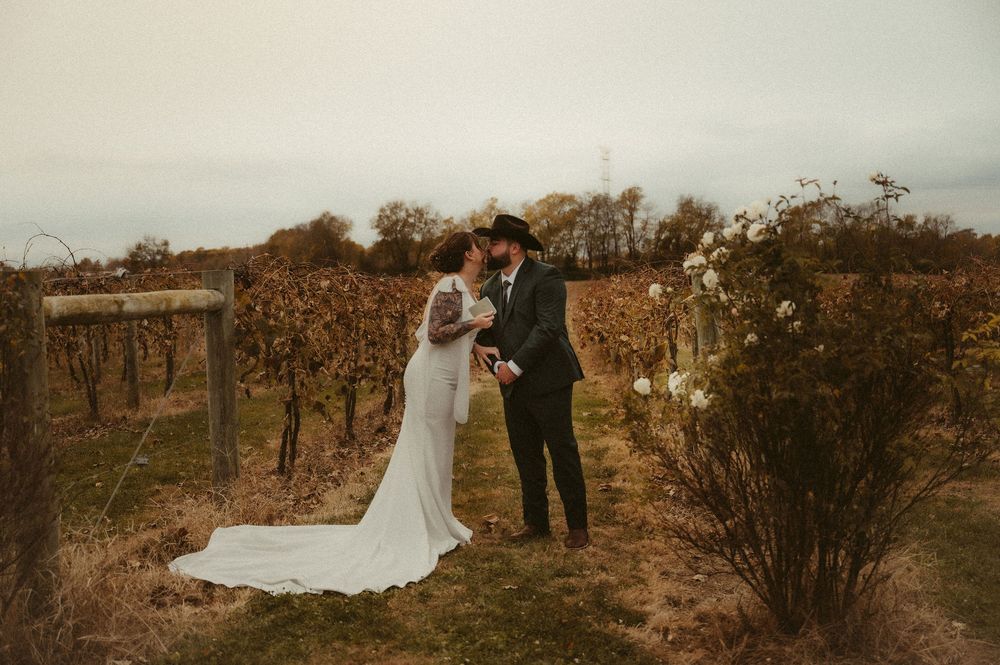 A romantic autumn wedding scene in a rustic vineyard with dried vines and warm golden light.