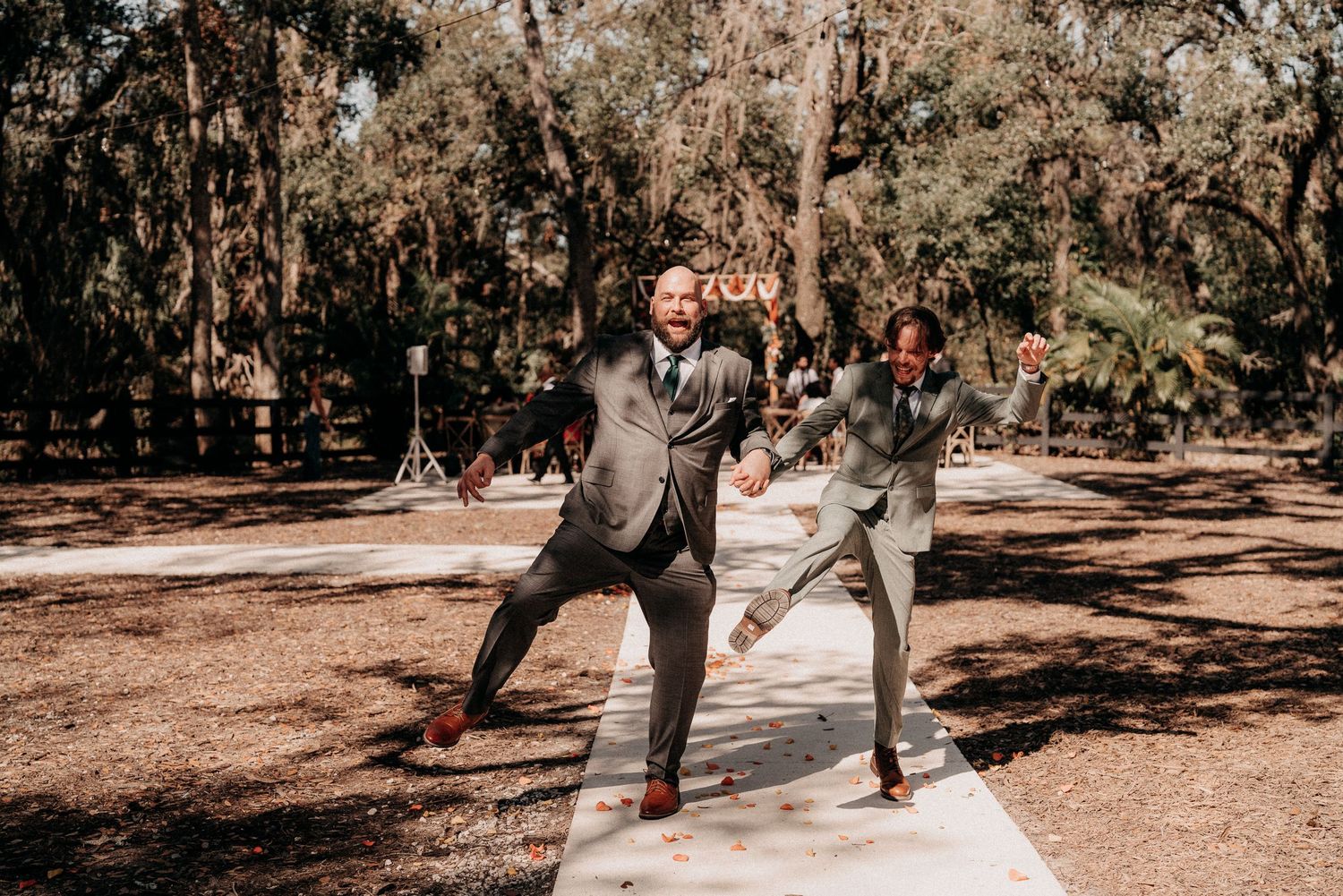 A couple performs a romantic dance move in a sunlit forest setting with dappled light filtering through the trees.