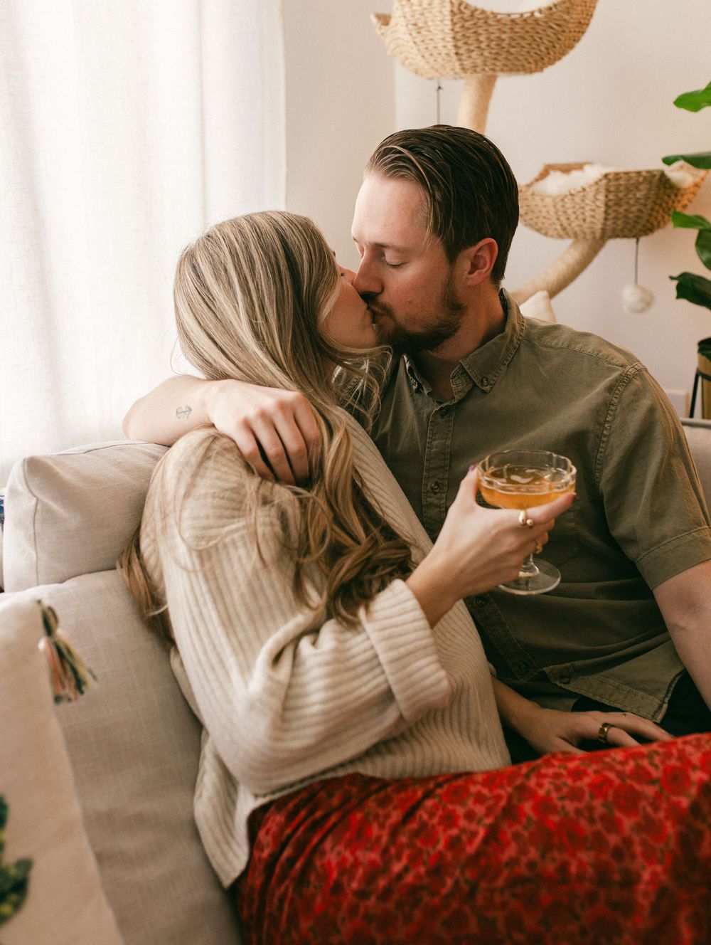A couple relaxing on a couch with a red throw blanket in a bright, modern living room.