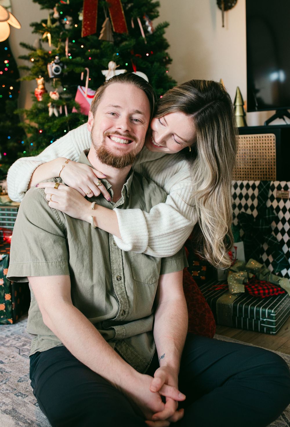 Romantic couple shares intimate moments by decorated Christmas tree in cozy living room setting.