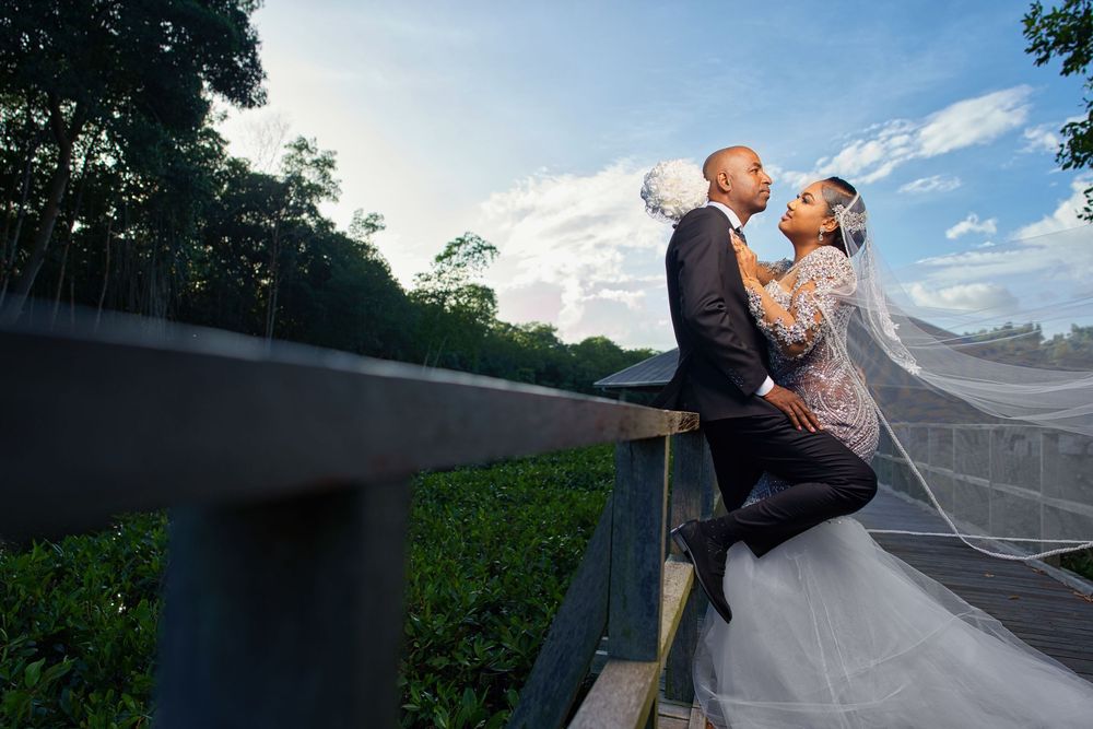 A couple shares a romantic moment on a rooftop terrace during sunset with lush greenery in the background.