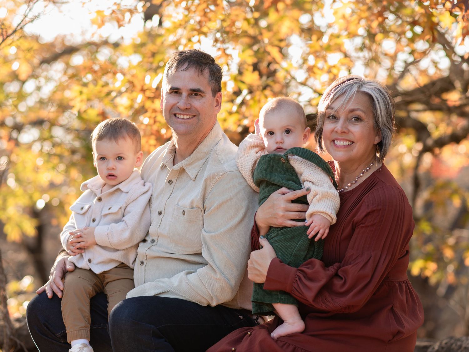 Grandparents holding grandchildren during extended family session at McKinney Falls State Park in Texas