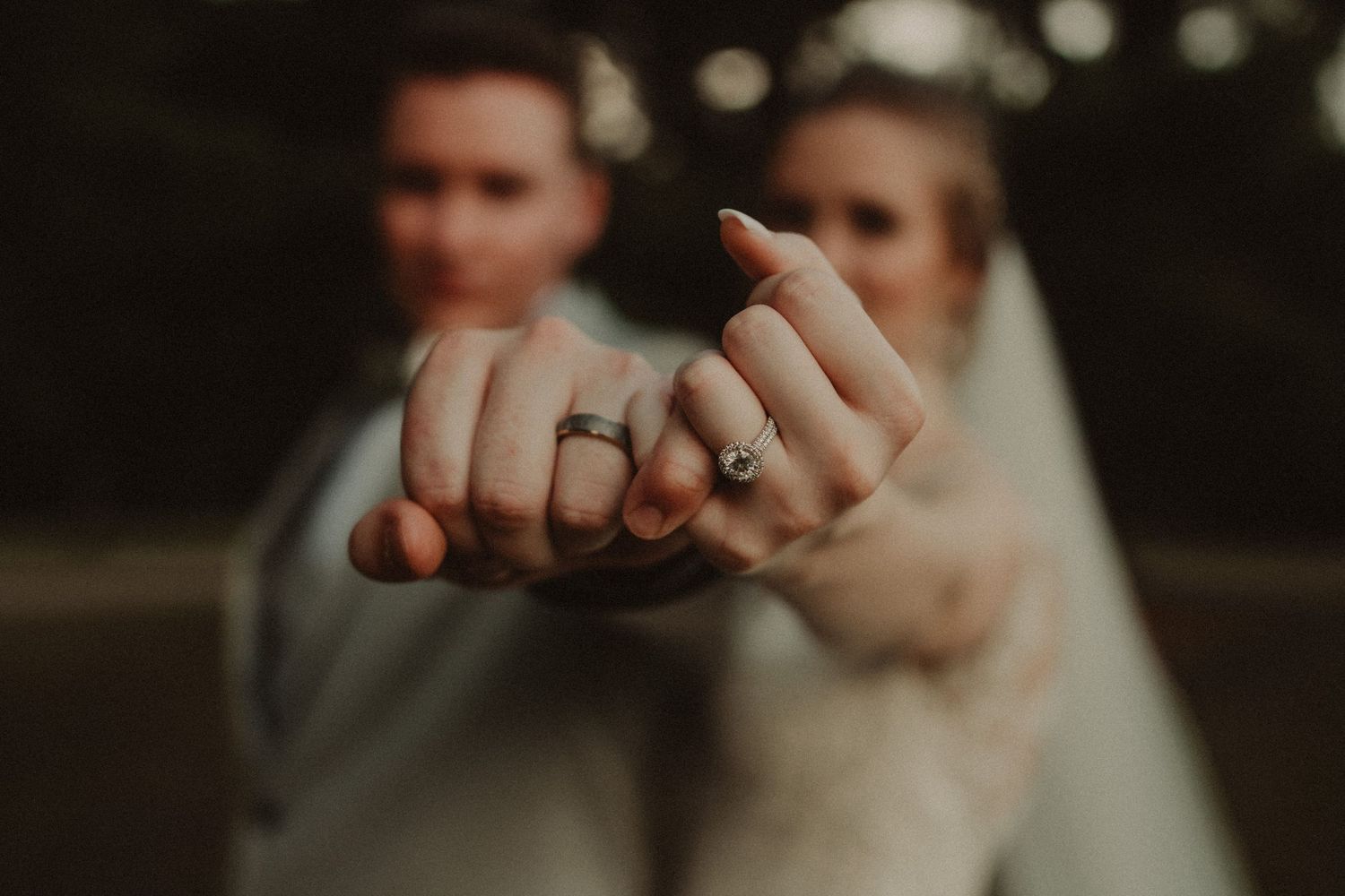 Close-up view of hands with wedding rings exchanging a gentle touch in soft natural lighting.