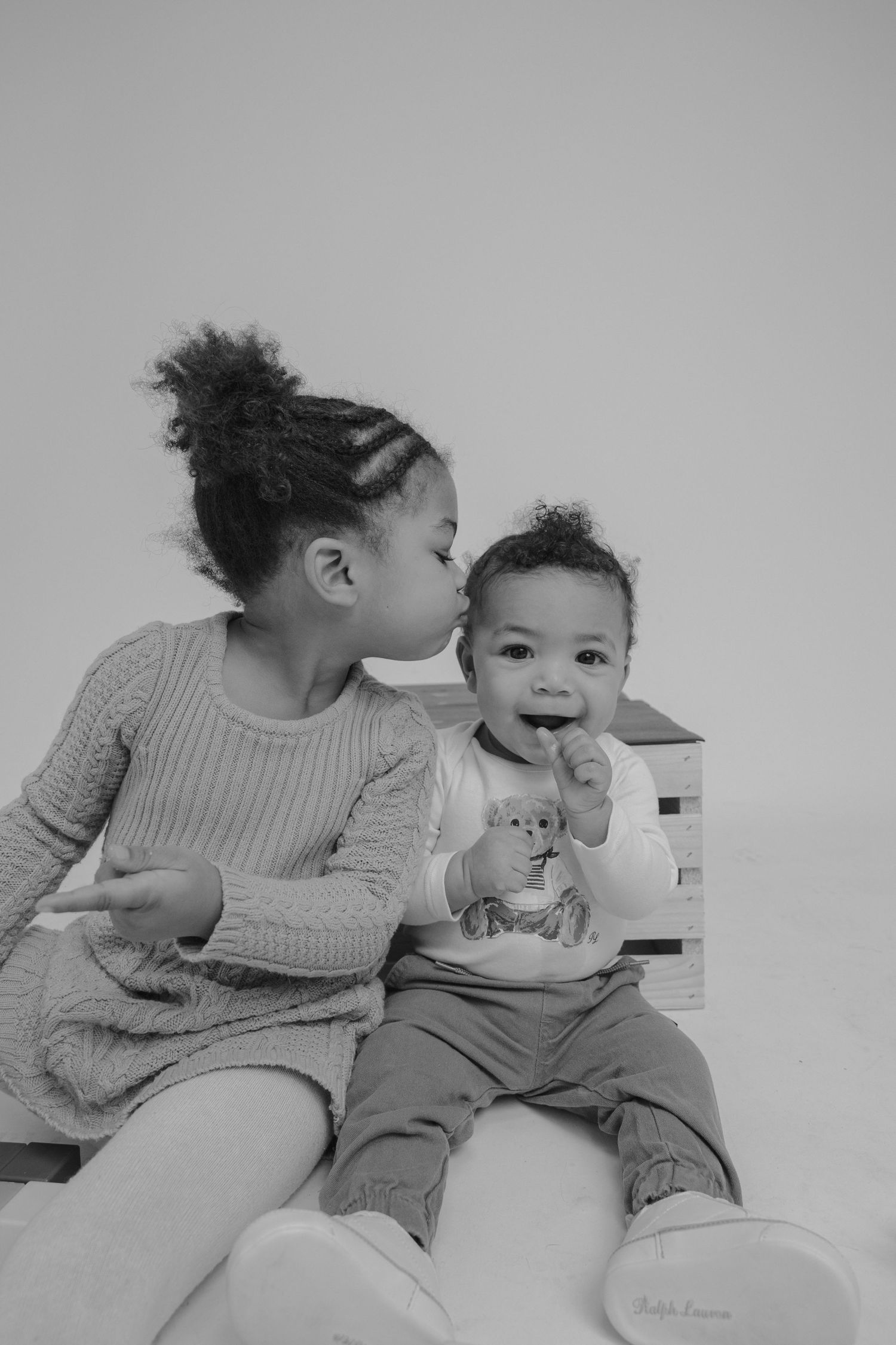 A series of black and white photos showing tender moments between a parent and baby sharing kisses and laughter.