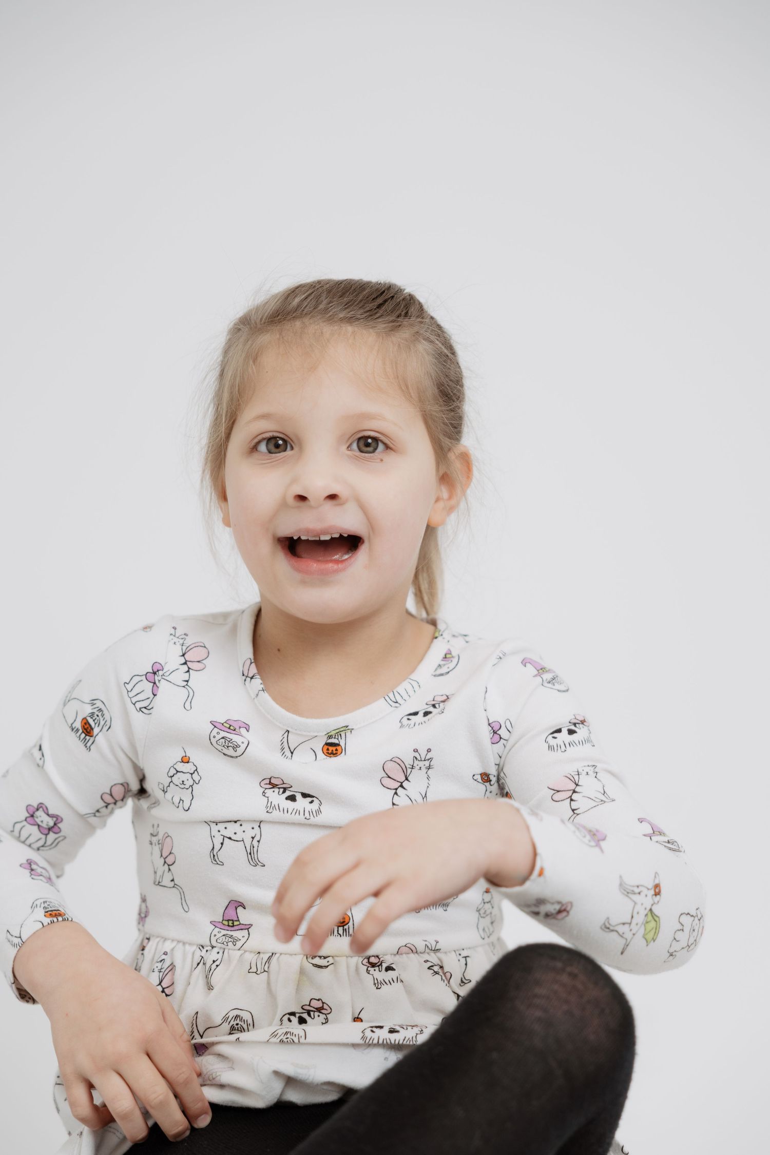 Child wearing a white long sleeve shirt with cute animal print design smiling and playing.