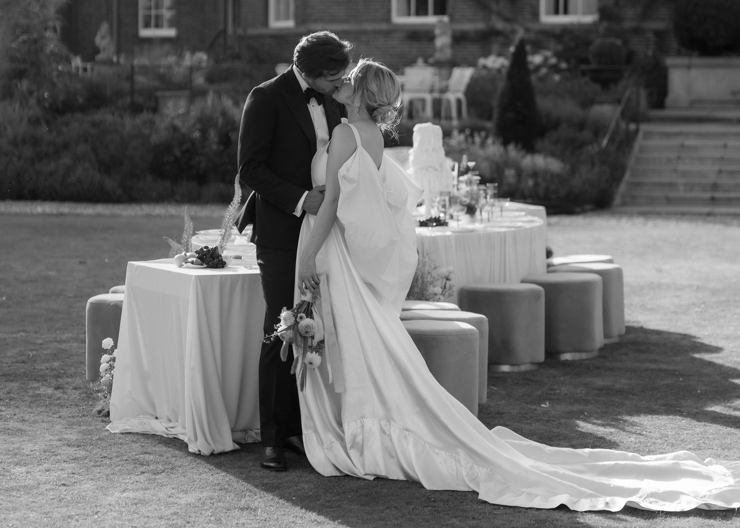 A black and white wedding photo collage showing intimate moments between a couple seated at outdoor reception tables.