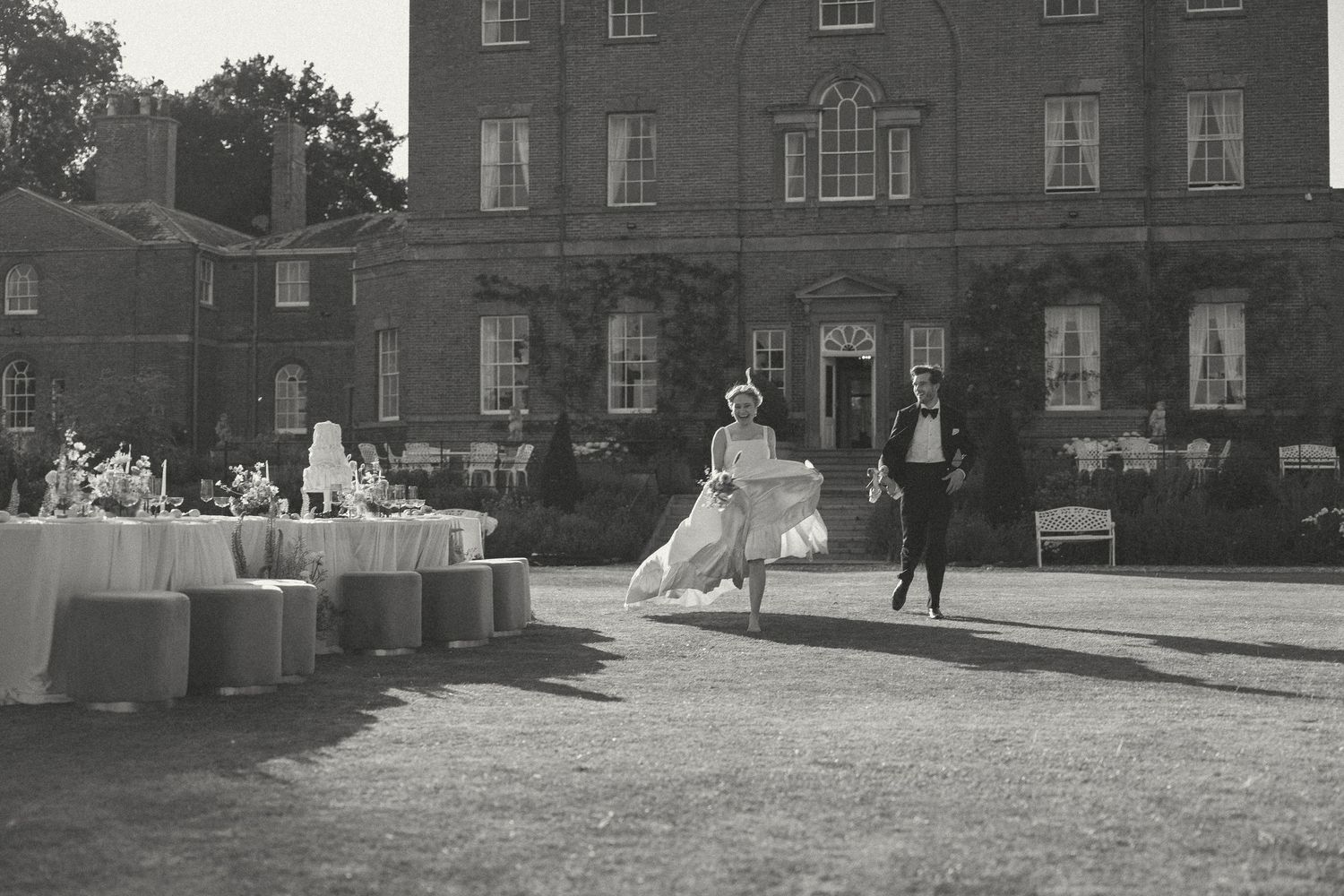 A black and white panoramic photograph shows a historic brick building with a courtyard and multiple architectural details.