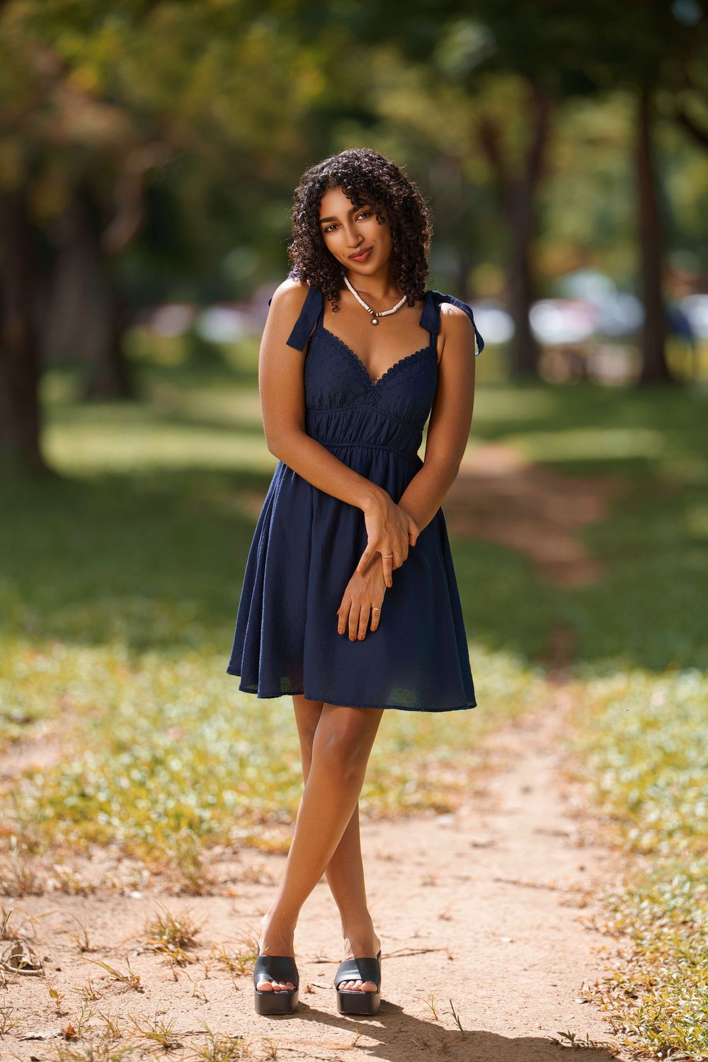 A playful outdoor photoshoot featuring a navy blue dress against a path with scattered white flowers.