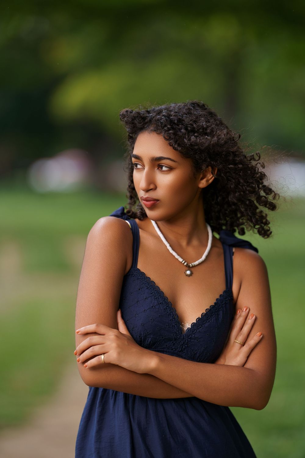 A navy blue dress is shown against a blurred green park background with warm sunlit highlights.