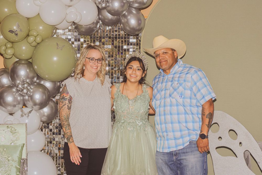 A group photo taken at a party with silver and green balloon decorations in the background.