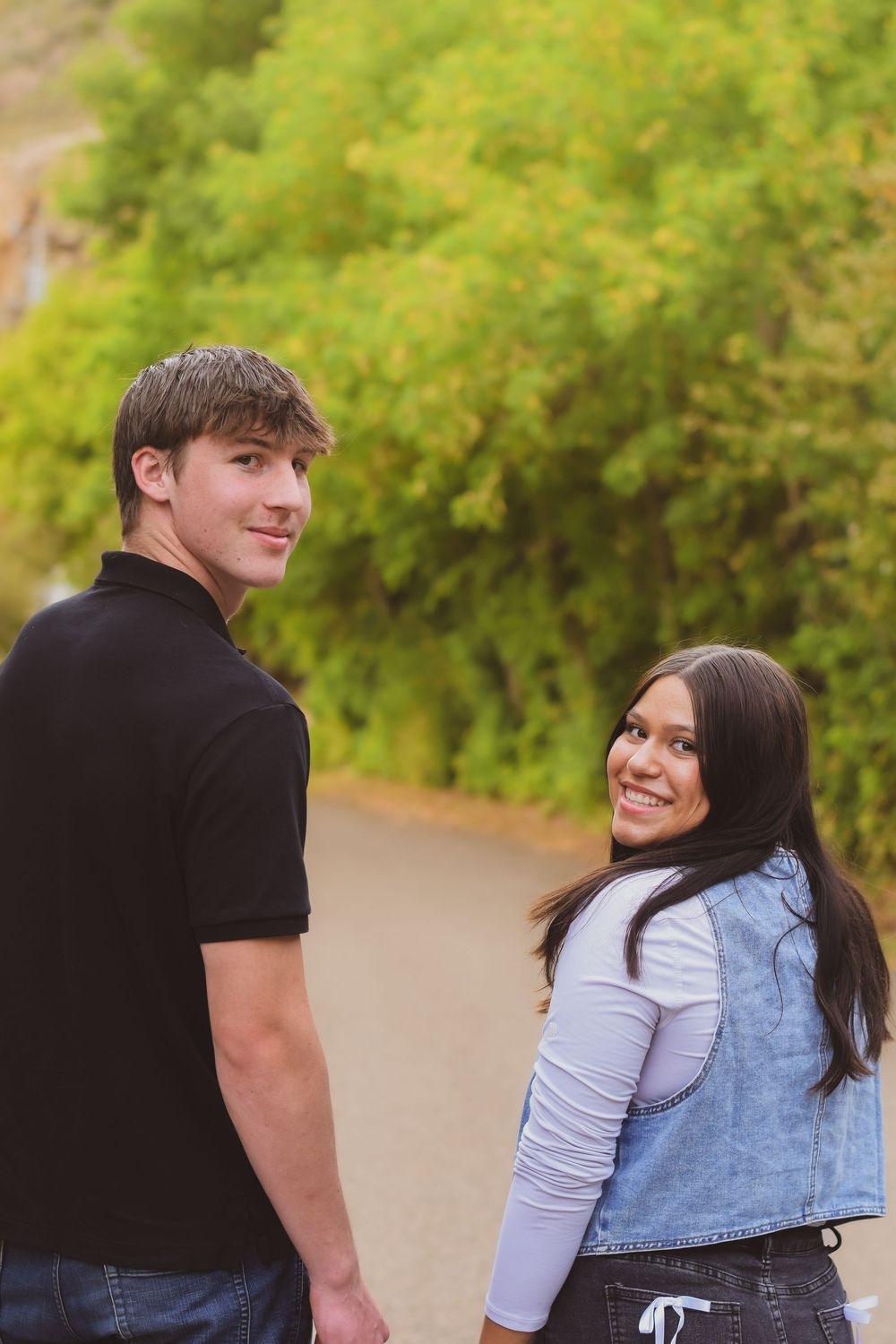 A couple shares a tender moment together outdoors against a backdrop of green foliage.