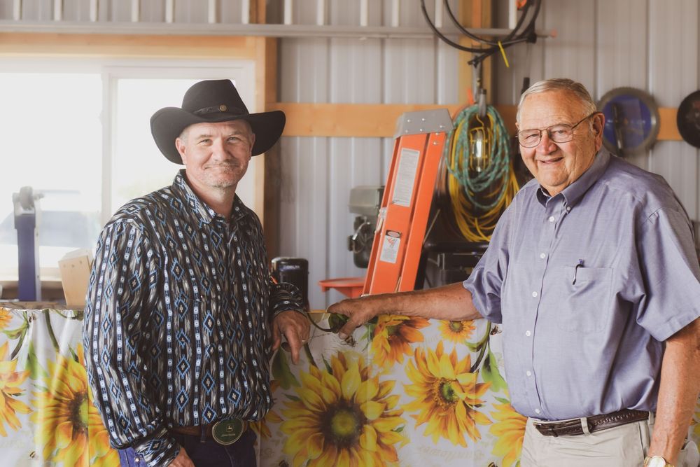 Seniors smile and socialize in front of a wall decorated with bright yellow sunflower artwork.