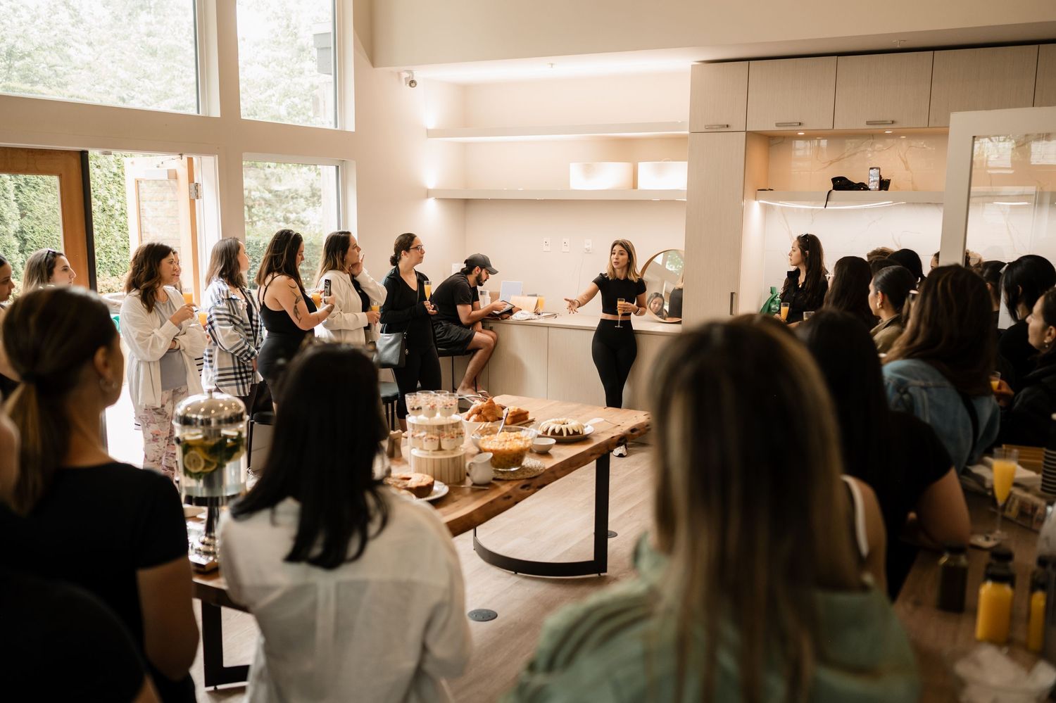 People gathering in a bright indoor space with raised arms.
