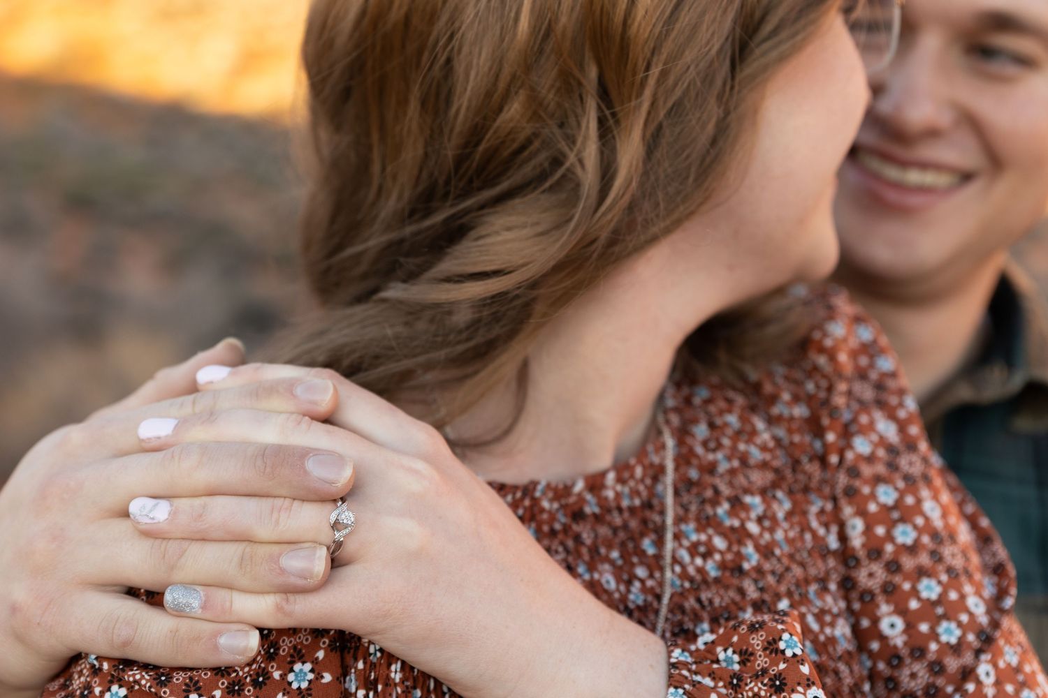 detail photographer in st George utah focus on a couples hands on Womens shoulder smiling at each other showing off engagement ring